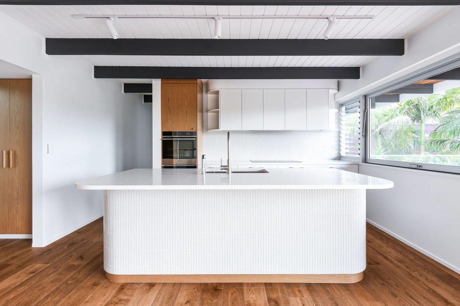 Modern kitchen with white cabinetry, timber veneer pantry and a tiled island bench