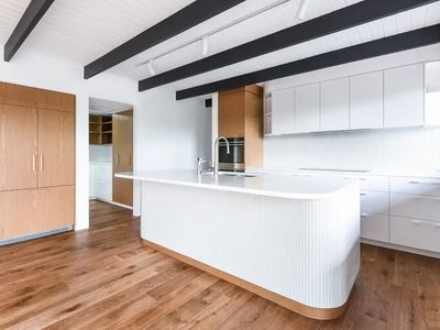 White kitchen with fluted island bench and timber joinery